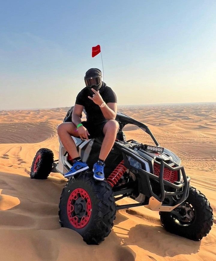 Guest geared up with helmet on the dune buggy, dunes stretching behind