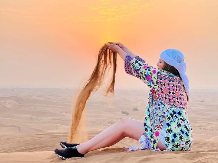 Guest playing with golden sand at sunset during the quad bike tour