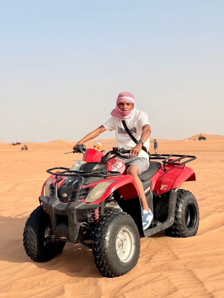 Guest posing on a red quad bike on the golden sands of Al Khatim