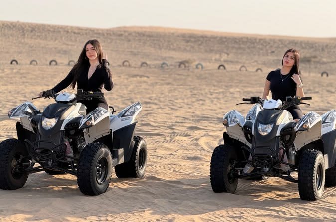 Two guests riding quad bikes across the Al Khatim dunes