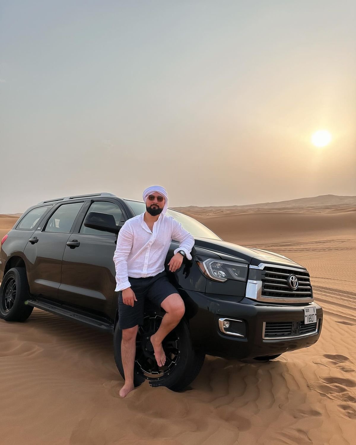 Land Cruiser and guest at sunset on the Al Khatim dunes – evening desert safari Abu Dhabi