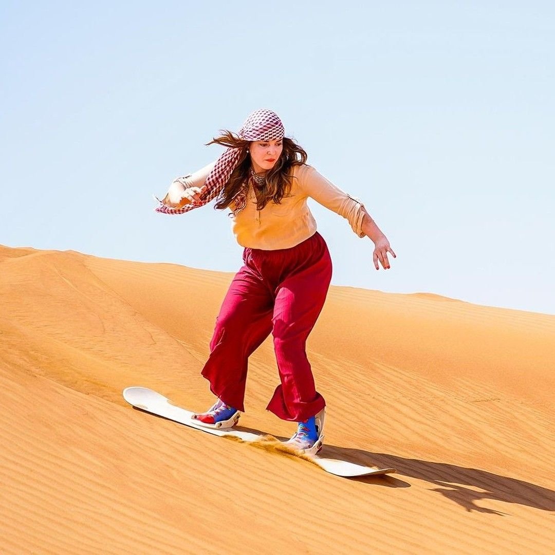 Guest sandboarding down the golden Al Khatim dunes