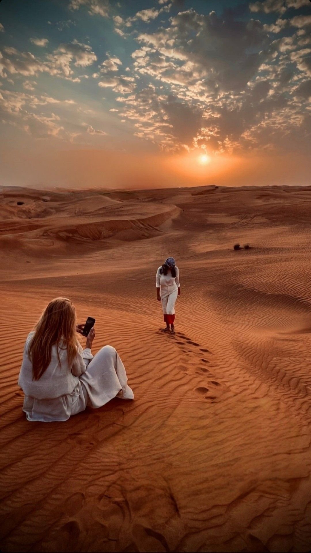 Guests photographing the sunset over the red dunes of the Al Khatim desert, Abu Dhabi