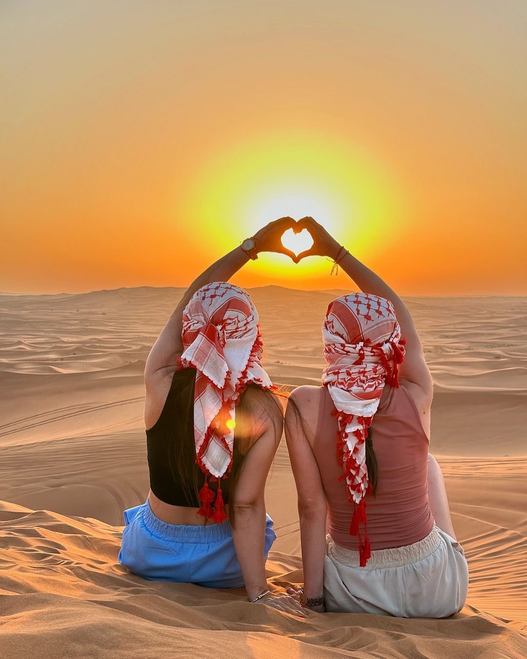 Guests making a heart around the sunrise on the Al Khatim dunes – morning desert safari Abu Dhabi