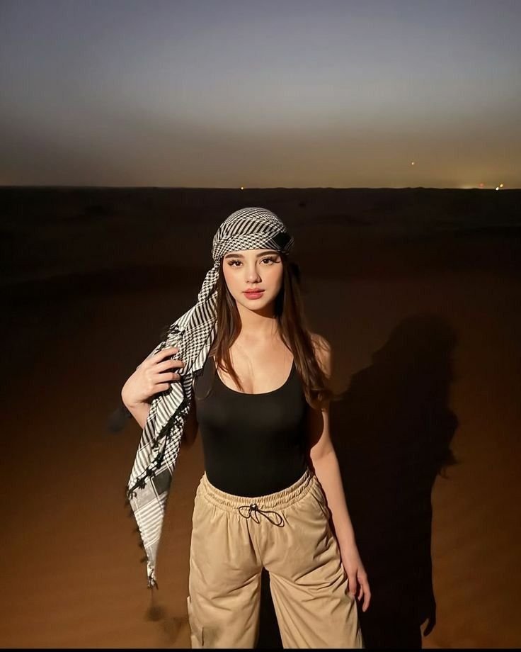 Guest in a keffiyeh on the dunes after dark – overnight desert safari Abu Dhabi