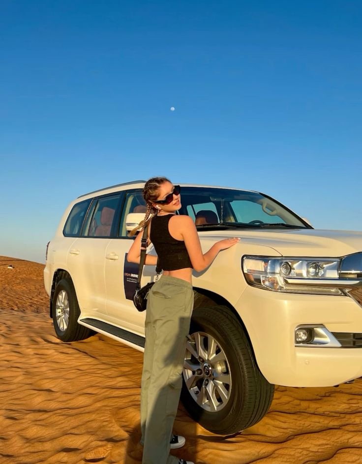 Guest beside the safari Land Cruiser at golden hour – overnight desert safari