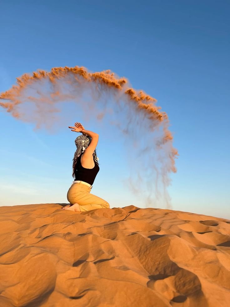 Guest tossing golden sand into the evening sky on the Al Khatim dunes