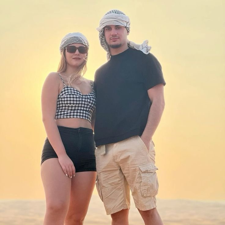 Couple in keffiyehs on the golden Al Khatim dunes at sunset – private desert safari Abu Dhabi