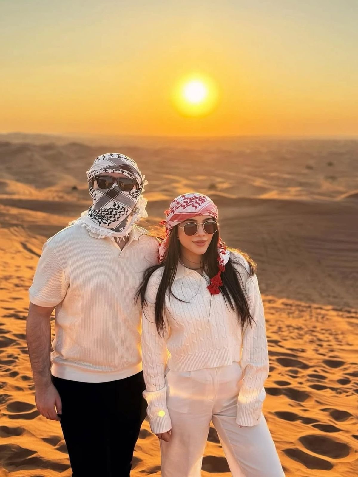 Couple in keffiyehs at golden sunset on a private desert safari