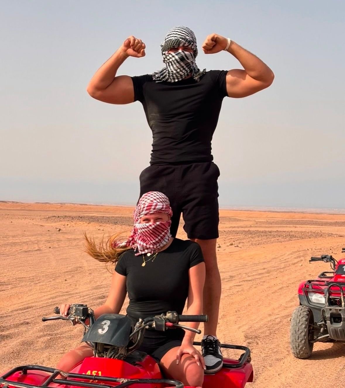 Couple having fun with red quad bikes on a private desert safari in Abu Dhabi