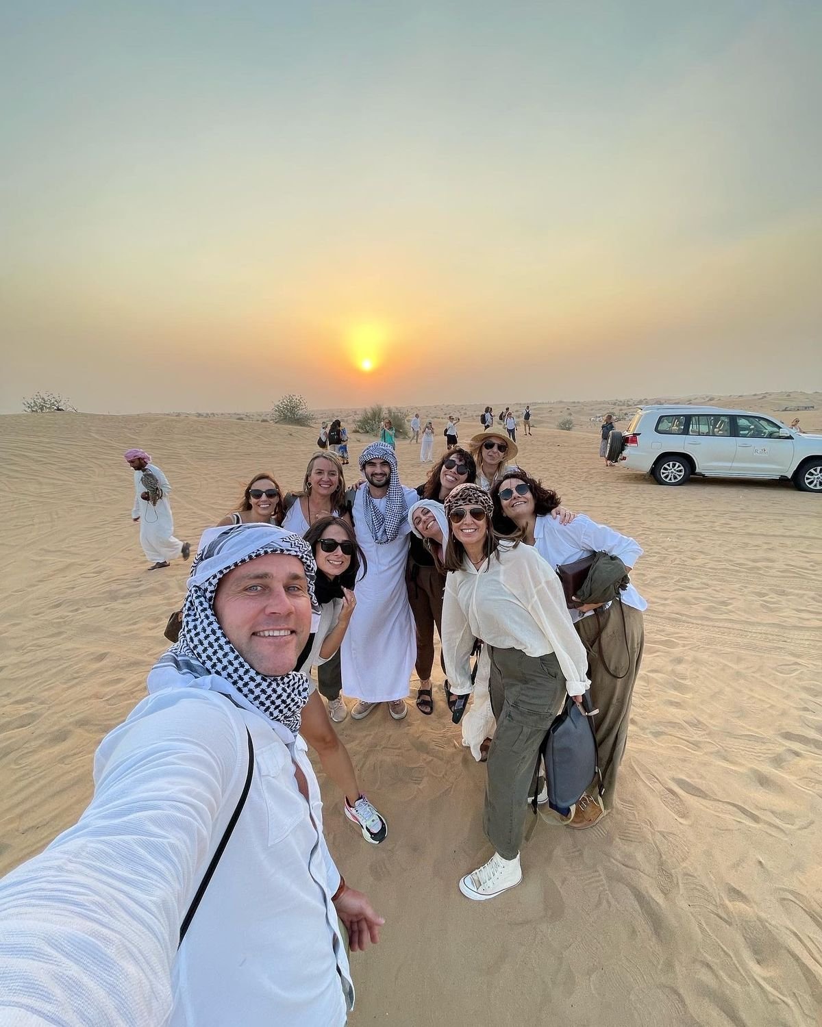 Tour group selfie at sunset with the falcon handler – VIP desert safari tour
